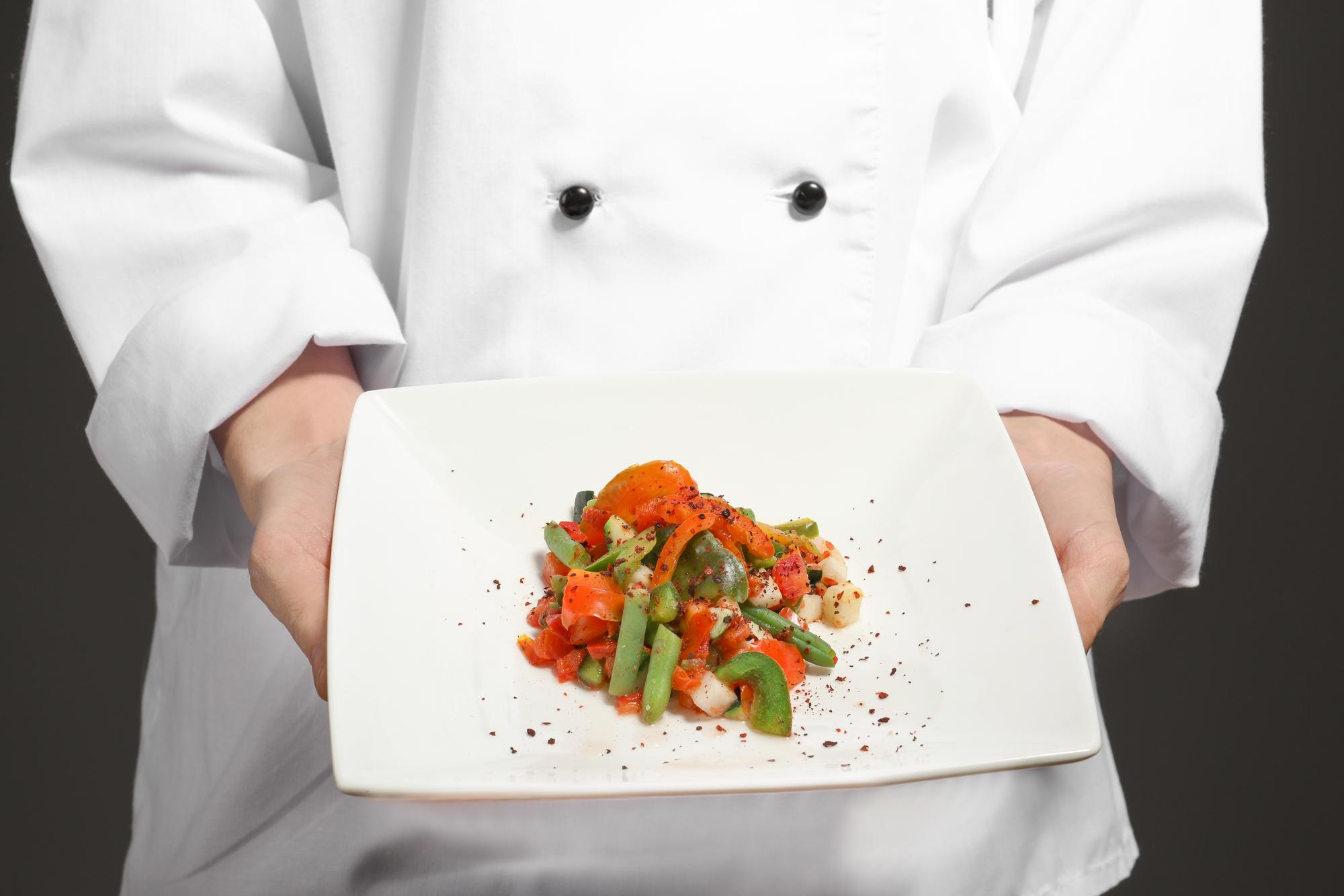 Instructor demonstrating plated dish in a warm kitchen